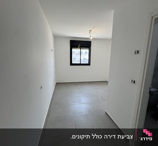 חדר ריק עם קירות לבנים ורצפת אריחים אפורה